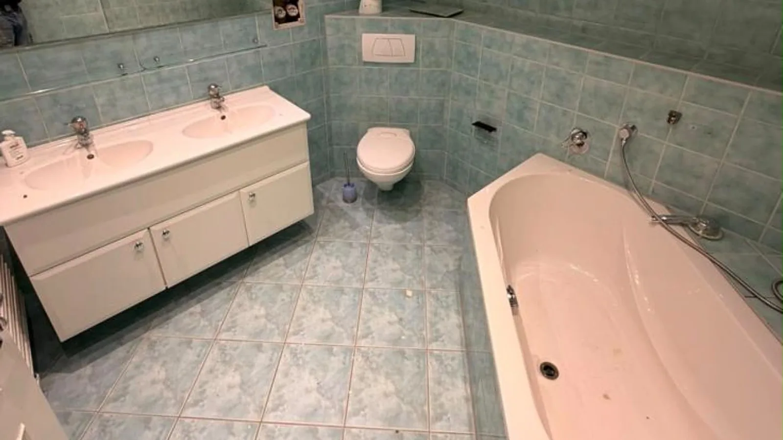 Altes Bad vor der Sanierung mit türkisfarbenen Fliesen, Doppelwaschtisch und Badewanne