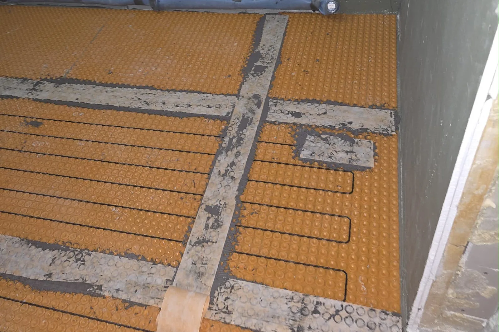 Heizkabel einer elektrischen Fußbodenheizung in der orangefarbenen Entkopplungsmatte, bereit zum Fliesen